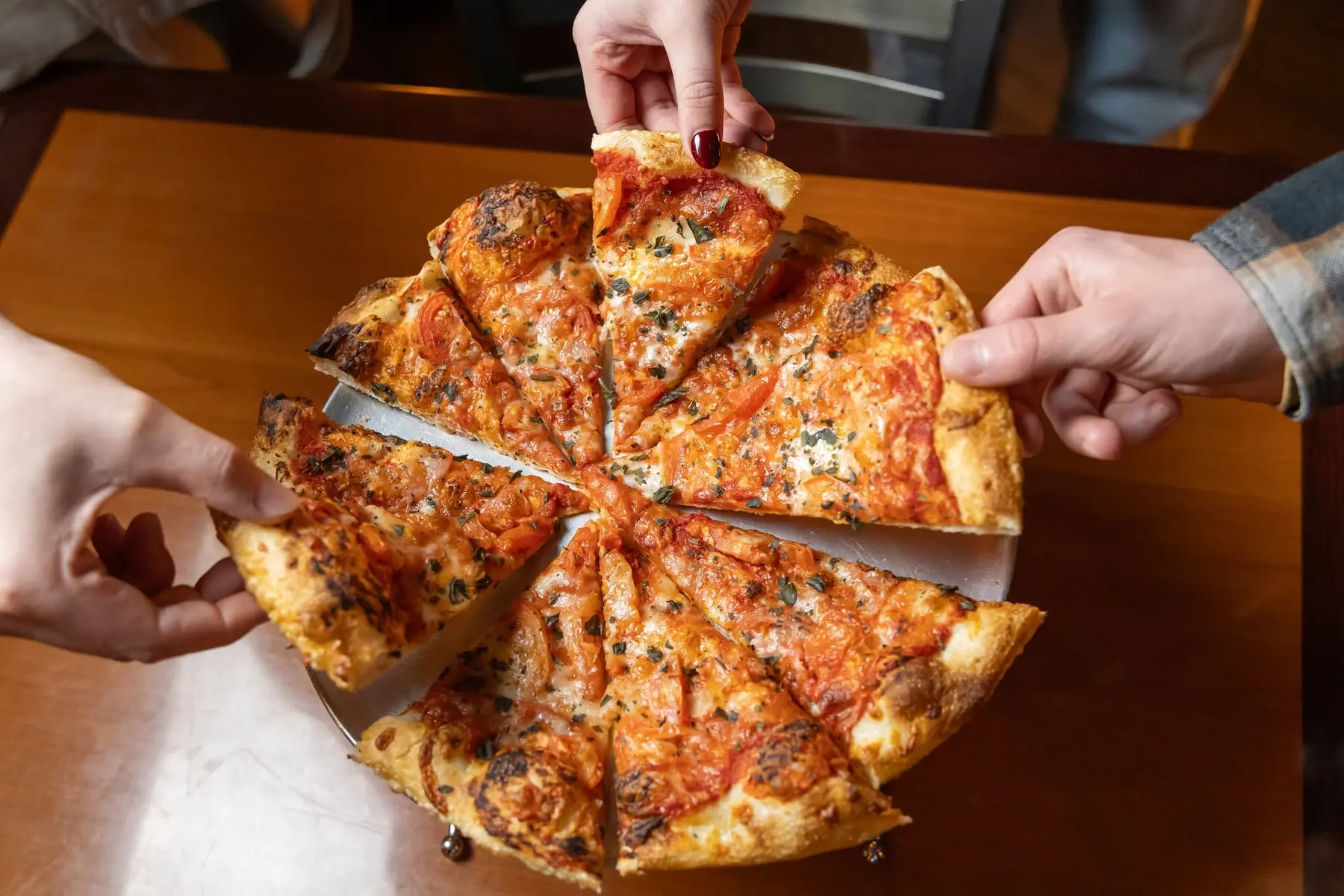 Friends sharing a fresh pizza at Dough Trader